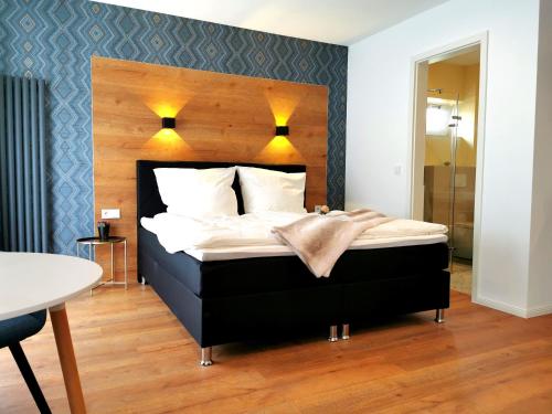a bedroom with a black bed with a wooden headboard at Gasthaus am Henriettenhof in Grömitz