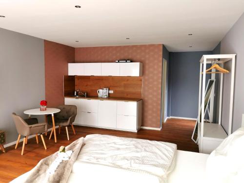 a bedroom with a bed and a table and a kitchen at Gasthaus am Henriettenhof in Grömitz