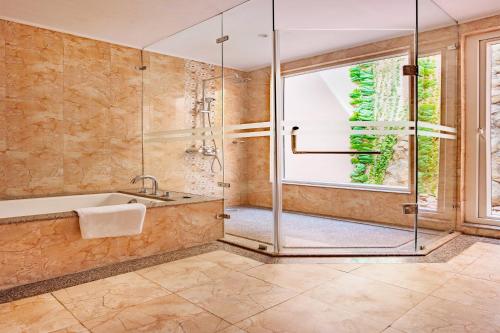 uma casa de banho com uma banheira e um chuveiro em vidro. em Orchha Palace and Convention Centre em Orchha
