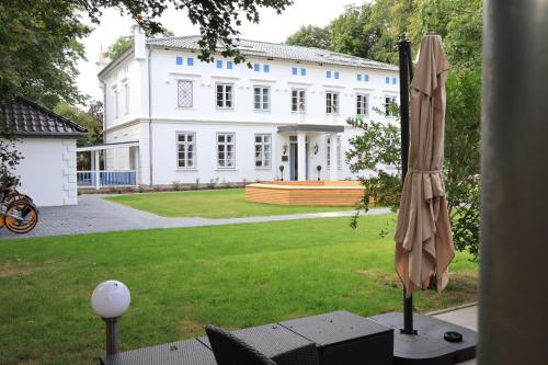 a large white house with an umbrella in the yard at Gasthaus am Henriettenhof in Grömitz
