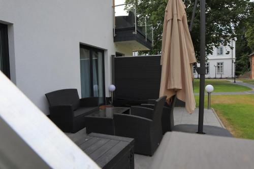 a patio with an umbrella and chairs and a table at Gasthaus am Henriettenhof in Grömitz