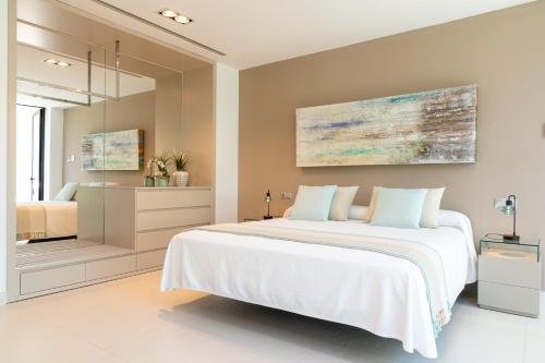 a bedroom with a large white bed and a mirror at Mont Blau in Búger