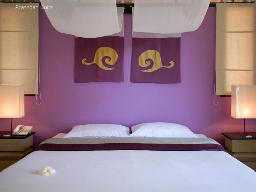 a bedroom with a bed with purple walls and two lamps at Praseban Resort in Pran Buri