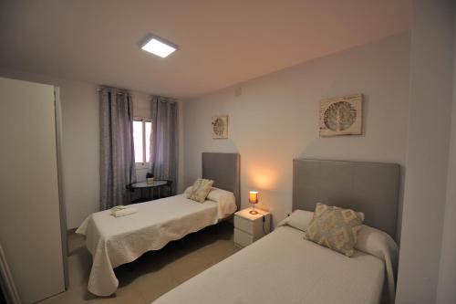 Habitación de hotel con 2 camas y ventana en Centrico Playa Caleta 3 dormitorios, en Cádiz