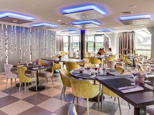 a restaurant with tables and chairs and people in the background at Novotel Orléans Saint Jean de Braye in Saint-Jean-de-Braye