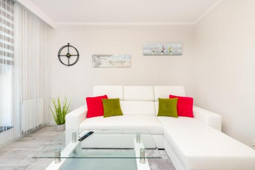 una sala de estar blanca con un sofá blanco con almohadas rojas y verdes en Apartamenty blisko Starego Miasta - Angielska Grobla by Noclegi Renters, en Gdansk