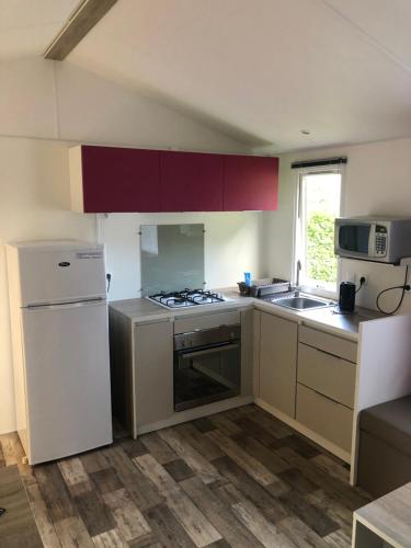 a kitchen with a white refrigerator and a stove top oven at Mobile Homes by KelAir at Camping L'Hippocampe in Argelès-sur-Mer