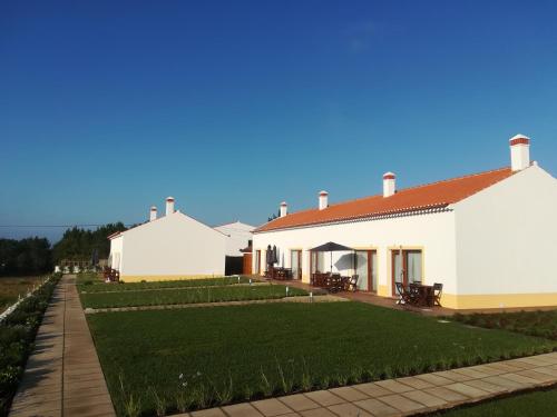 a large white building with a grass yard at Vila Lira in Aljezur