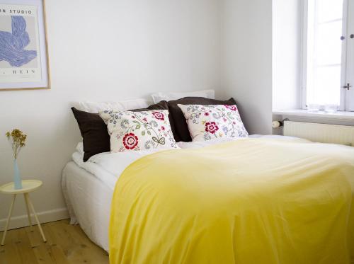 a bedroom with a bed with yellow sheets and pillows at Bright apartment next to the King's Garden in Copenhagen