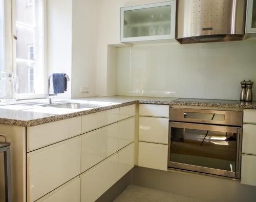 a kitchen with white cabinets and a sink and a stove at Bright apartment next to the King's Garden in Copenhagen
