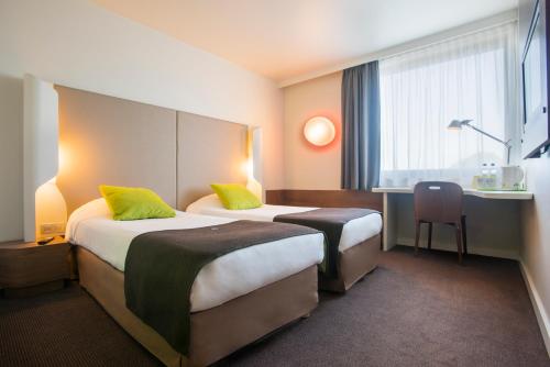 a hotel room with two beds and a desk at Campanile Bydgoszcz in Bydgoszcz