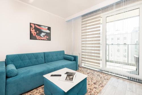 a living room with a blue couch and a table at Apartamenty blisko Starego Miasta - Angielska Grobla by Renters in Gdańsk