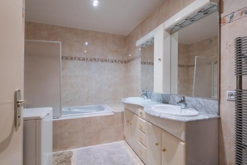 La salle de bains est pourvue de 2 lavabos, d'une baignoire et d'un miroir. dans l'établissement Fleur des Champs, à Saint-Germain