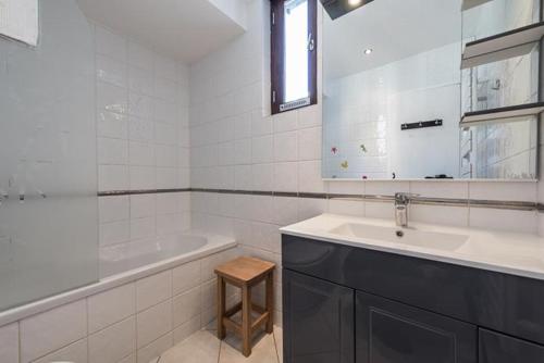 a white bathroom with a sink and a tub and a mirror at Studio 4 personnes au pied des pistes in Tignes
