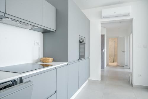 una cocina blanca con electrodomésticos blancos y un pasillo en Apartment Figtree Vodice, en Vodice
