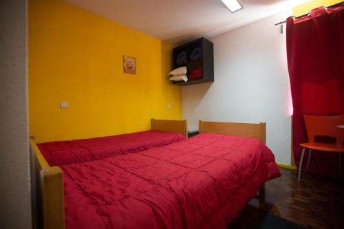 a bedroom with a red bed and a yellow wall at HI Aveiro – Pousada de Juventude in Aveiro