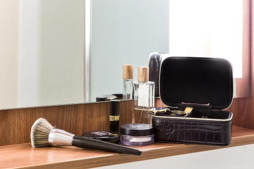 a bathroom counter with a makeup brush and cosmetics at Campanile Katowice in Katowice