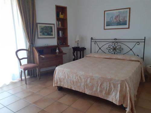 Schlafzimmer mit einem Bett, einem Schreibtisch und einem Stuhl in der Unterkunft VelaLatina Residence B&B Soverato - Camera Scirocco in Soverato Marina