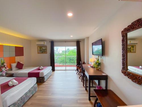 a room with two beds and a table and a mirror at East Inn 15 Rayong - SHA Certified in Rayong