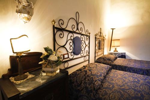 a bedroom with two beds and a table with a lamp at Antica Residenza Cicogna in Siena