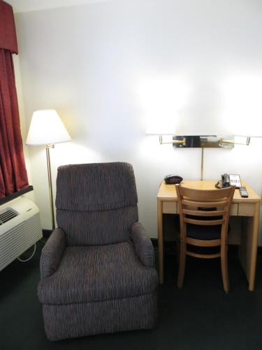 a room with a chair and a desk with a lamp at Baymont by Wyndham Wellington in Wellington