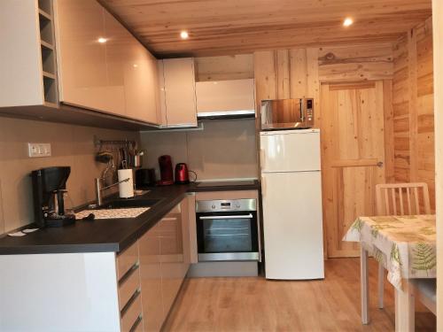 Il comprend une cuisine équipée d'un réfrigérateur blanc et d'une table. dans l'établissement Appartement 2 pièces cuisine Les Hermines, à Saint-Nicolas-la-Chapelle