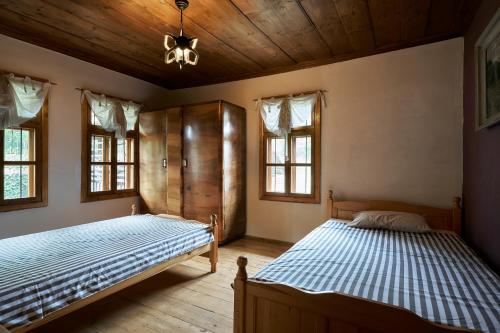 two beds in a bedroom with wooden ceilings and windows at Boutique guest house "SamiKan" in Elena