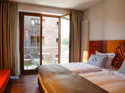 a hotel room with a bed and a large window at Hotel Begardenhof in Cologne