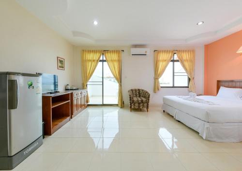 a bedroom with a bed and a desk and a refrigerator at Sun & Beach in Pattaya South