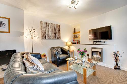 a living room with a leather couch and a fireplace at Greaves Wharf House in Porthmadog
