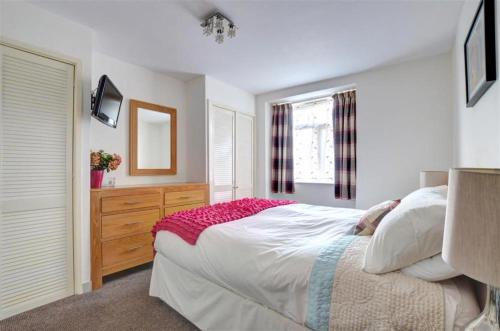 a bedroom with a bed and a dresser and a window at Greaves Wharf House in Porthmadog