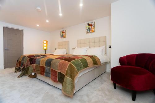 a bedroom with a large bed and a red chair at Westwood Apartment in Leeds