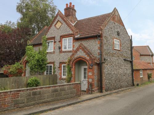 a brick house with a white door on a street at Compass Cottage in Holt