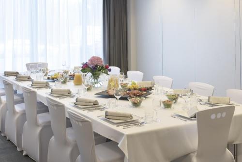 a long white table with white chairs and flowers on it at Campanile Wroclaw Centrum in Wrocław