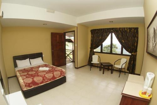 a bedroom with a bed and a table and chairs at Sunrise Kundasang Resort in Ranau