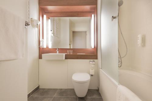 a bathroom with a toilet and a sink and a mirror at Campanile Wroclaw Centrum in Wrocław
