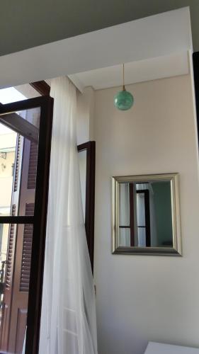 a window with a white curtain and a mirror at Theasis Athens in Athens