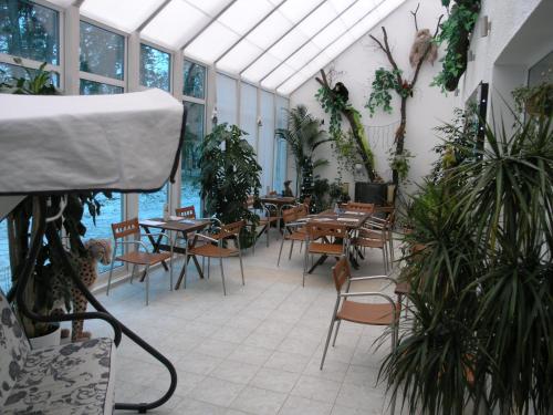 a dining room with tables and chairs and plants at SPA Hotel in Vorzelʼ