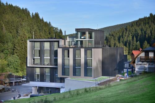 a building on the side of a hill with trees at Grand Hotel Hradec in Pec pod Sněžkou