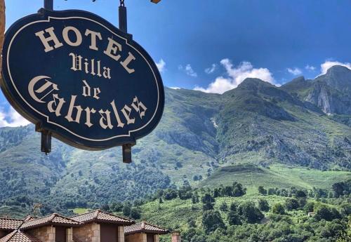 a sign for a hotel with mountains in the background at Hotel Villa de Cabrales in Arenas de Cabrales