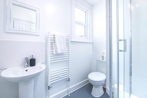 a white bathroom with a sink and a toilet at Grand Victoria Seaside Beauty, Stones-Throw from the Beach in Weston-super-Mare