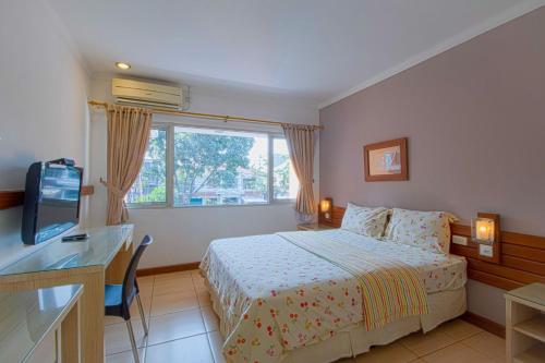 a bedroom with a bed and a desk and a television at Applewood B&B in Bogor