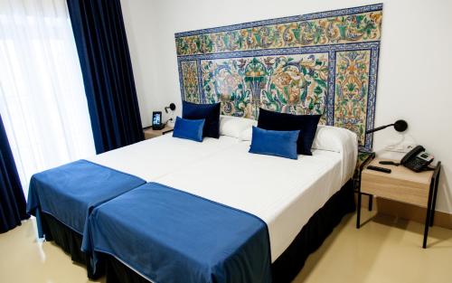 a bedroom with a large bed with blue pillows at HOTEL TRIANA MONTALVAN in Seville