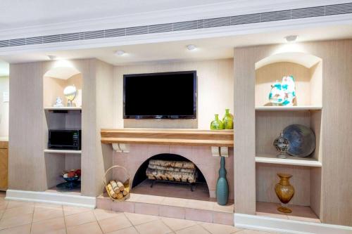 a living room with a fireplace with a flat screen tv at La Quinta East Deerfield Beach - Boca Raton in Deerfield Beach