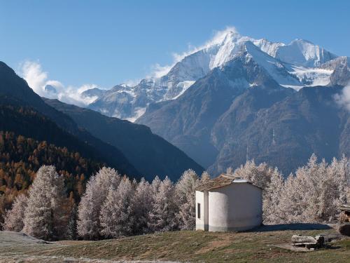 a small building on a hill with mountains in the background at Chalet Soldanella in Grächen