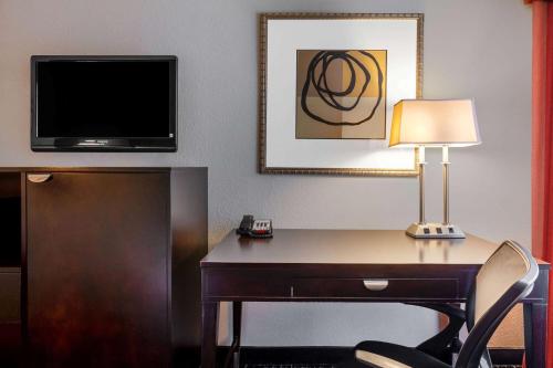a hotel room with a desk with a lamp and a tv at La Quinta by Wyndham Lumberton in Lumberton