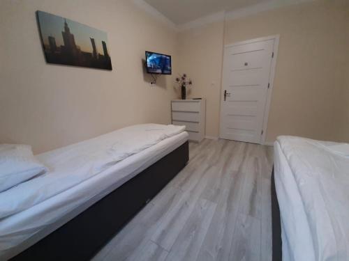 a bedroom with two beds and a dresser and a door at Warszawska in Legionowo