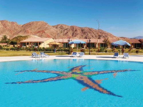 a reflection of a woman in the water of a pool at Movenpick Taba Resort & Spa in Taba