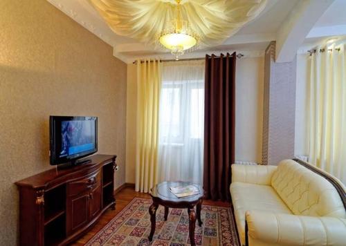 a living room with a white couch and a tv at VICTOR Hotel Resort & SPA in Truskavets