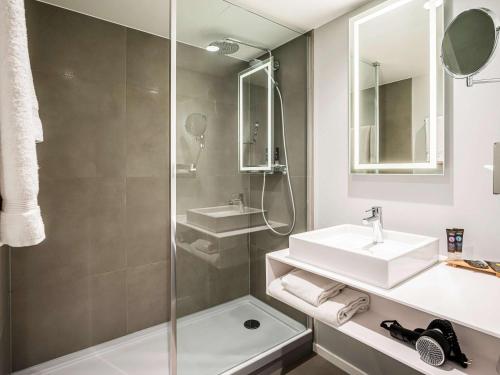 a bathroom with a shower, sink, and mirror at Novotel Den Haag City Centre, fully renovated in The Hague